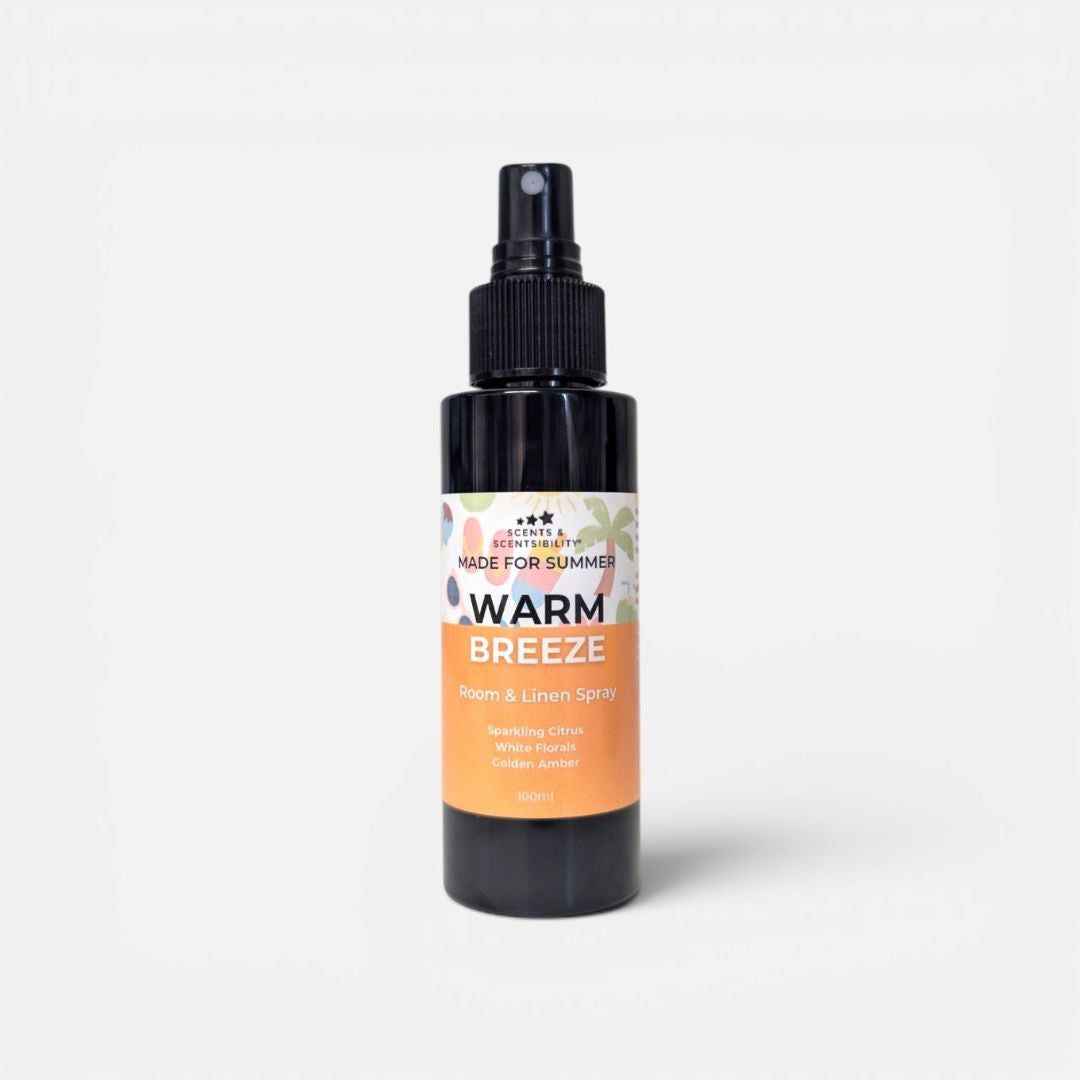 A black bottle of room spray with a colourful label which says 'Warm Breeze'
