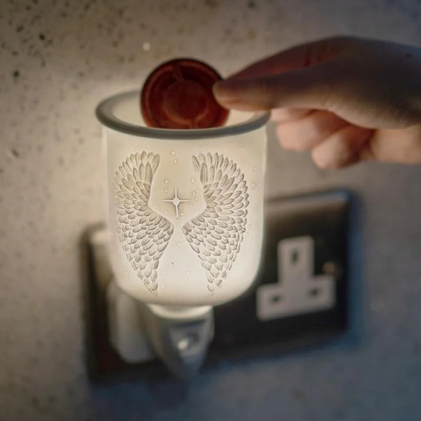 Hand inserting a wax melt into a decorative wax warmer.