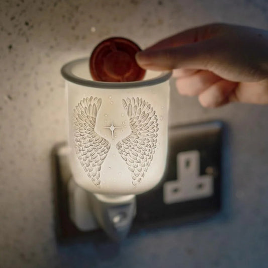 Hand inserting a wax melt into a decorative wax warmer.
