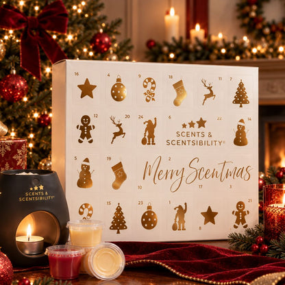 Scents & Scentibility Merry Scentmas advent calendar box in a warm holiday setting with candles, ornaments, and a Christmas tree in the background.