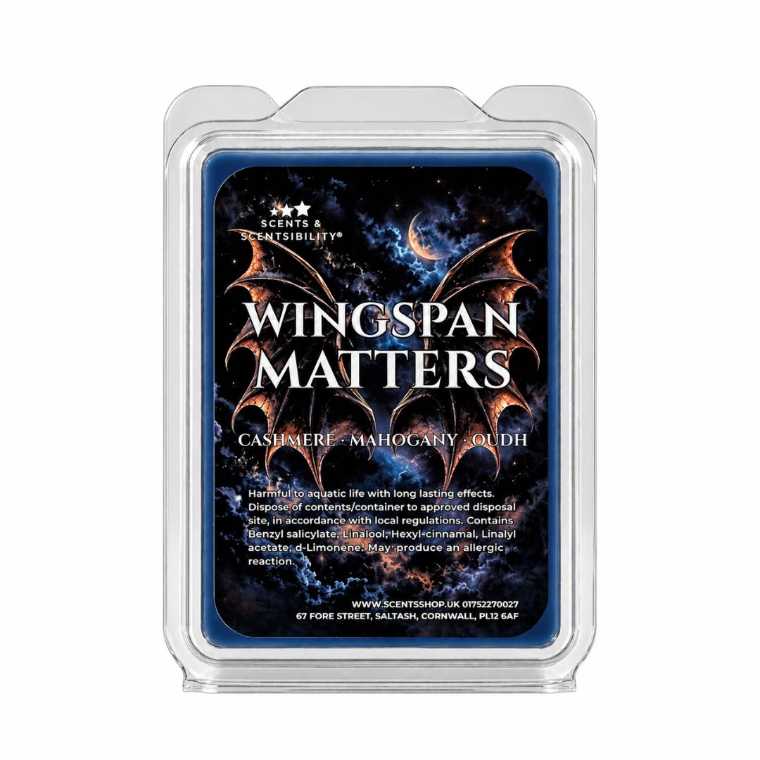 A clear plastic clamshell package containing a blue scented melt bar labeled 'Wingspan Matters' with fantasy dragon artwork and text reading 'Cashmere - Mahogany - oudh'.