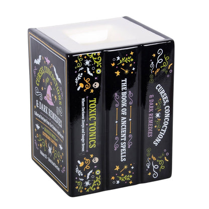 A black, decorative wax melt and oil burner, shaped like a stack of books about ancient spells and curses