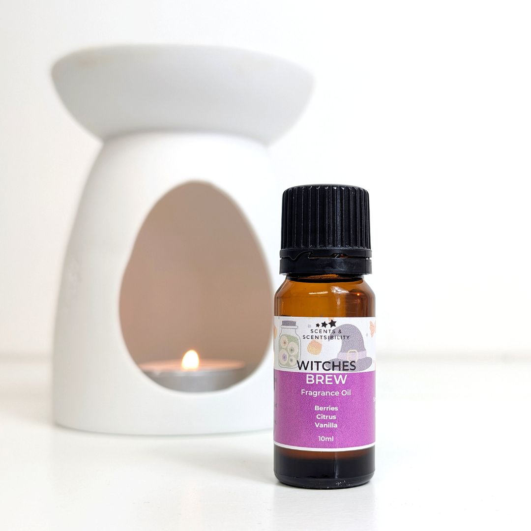 Bottle of 'Witches Brew' fragrance oil with a white wax melt and oil burner on a white background