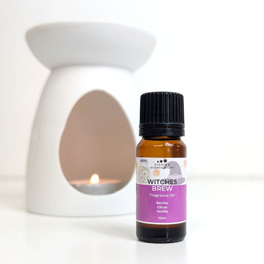 Bottle of 'Witches Brew' fragrance oil with a white wax melt and oil burner on a white background