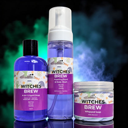 Three Witches Brew branded personal care products displayed together: a blue bottle of 4-in-1 liquid soap, a tall clear bottle with a white pump of foaming hand & body wash, and a clear jar of whipped soap, all with purple labels, set against a dark smoky background with green and blue glow.