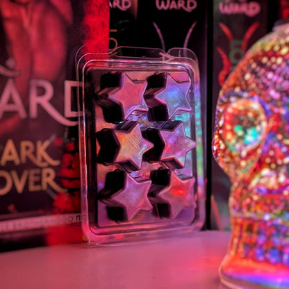 A black wax melt in a star-shaped clamshell