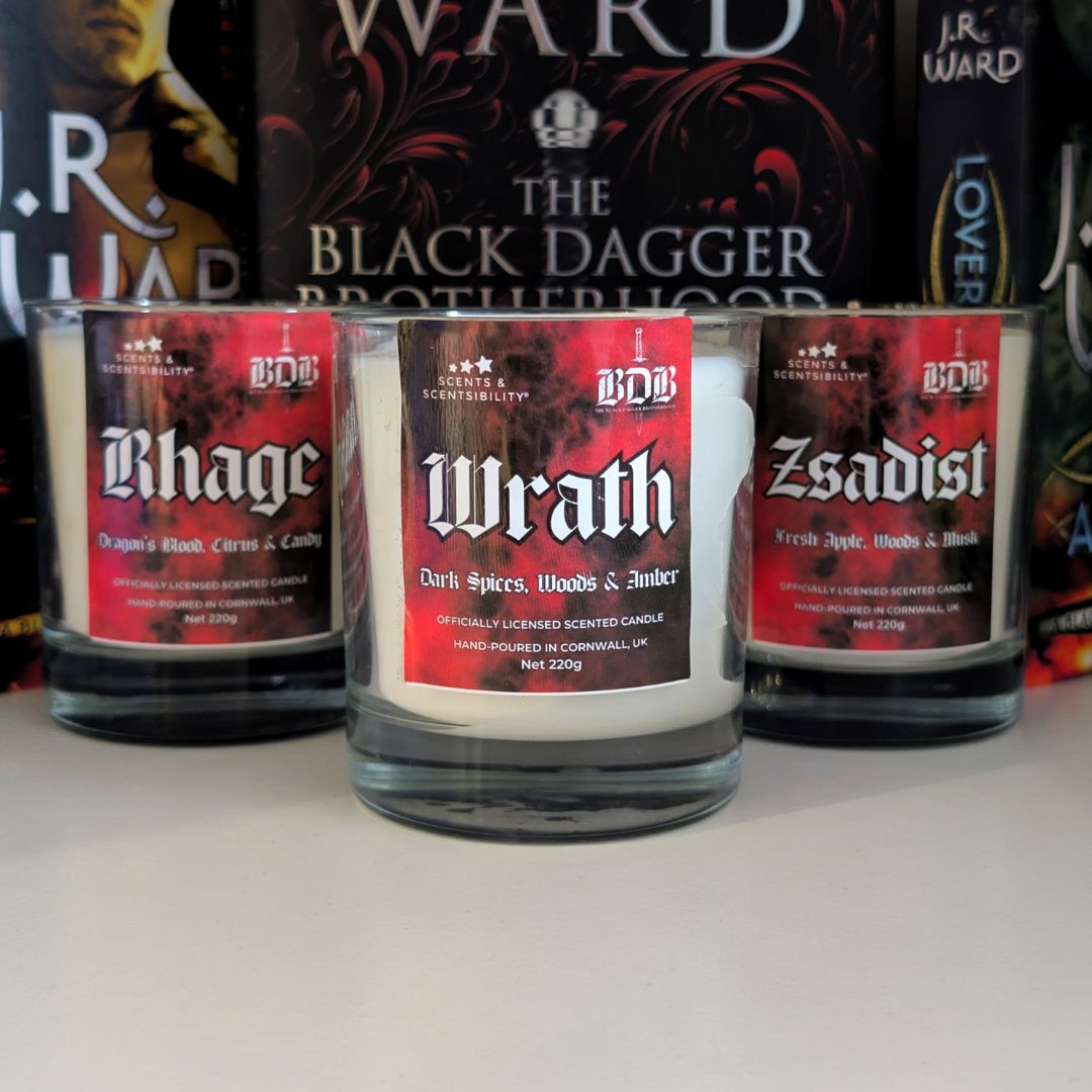 Three scented candles labeled 'Rhage', 'Wrath', and 'Zsadist' on a white surface with books in the background.
