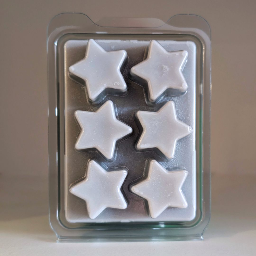 Star-shaped white wax melts in a clear plastic mold on a beige background