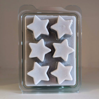Star-shaped white wax melts in a clear plastic mold on a beige background