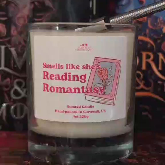 A video of a candle, labelled Romantasy, in front of books