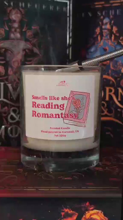 A video of a candle, labelled Romantasy, in front of books